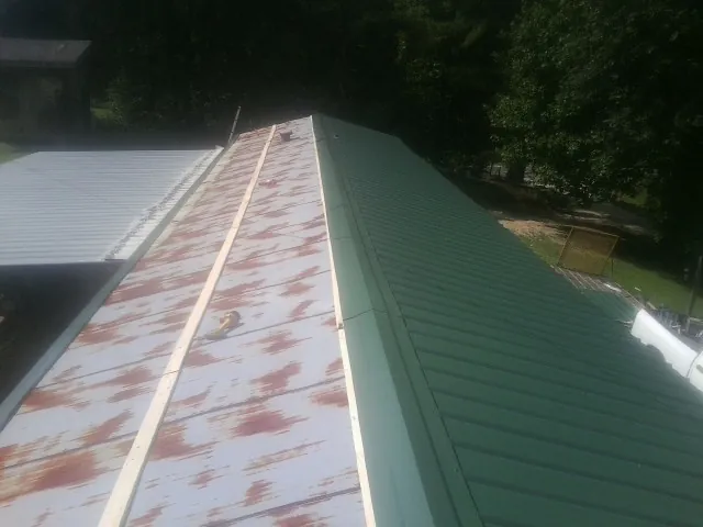 Old rusted panels beside newly installed green metal roofing — Wind Damage Roof Repair by Roofing Brothers in Summit