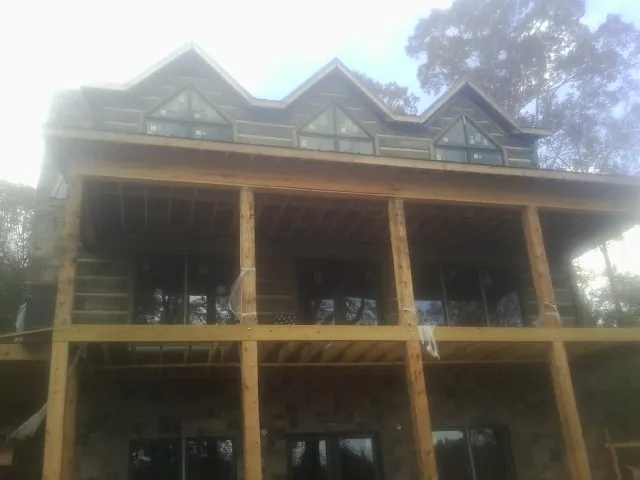 Dormers and porch framing on a large log home under construction — Roof Coating work by our crew in Summit