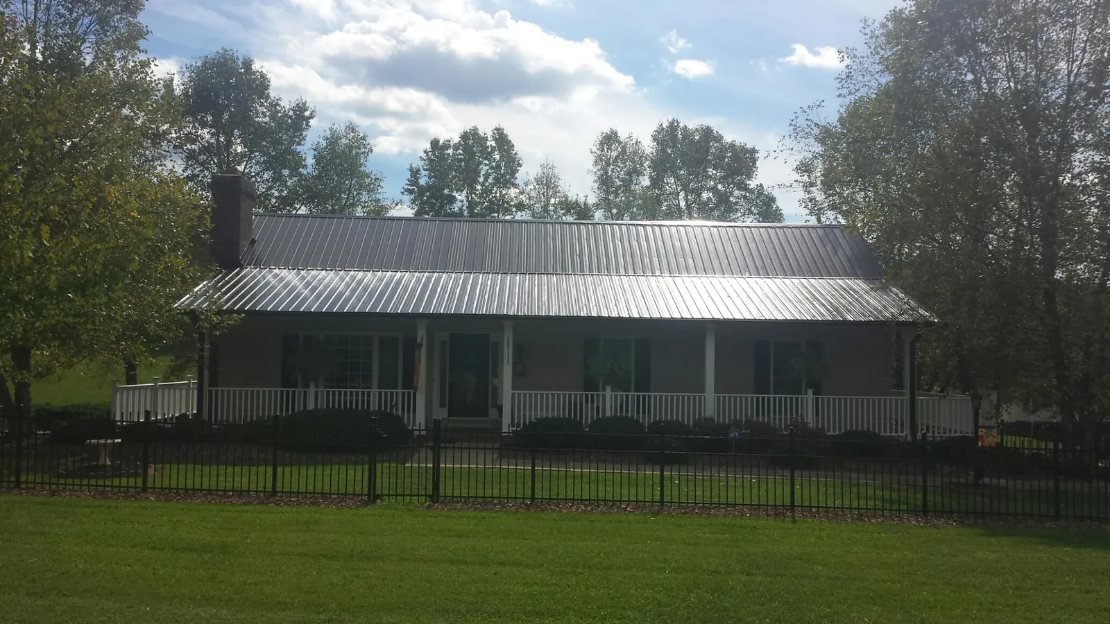 Gray metal roof on a brick ranch with a full width front porch — Gutter Guard Installation work by our crew in Summit